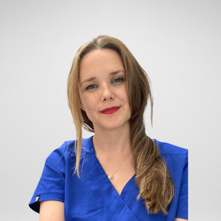 Stomatolog Ortodonta Monika Żbikowska w niebieskim fartuchu, uśmiechnięta.