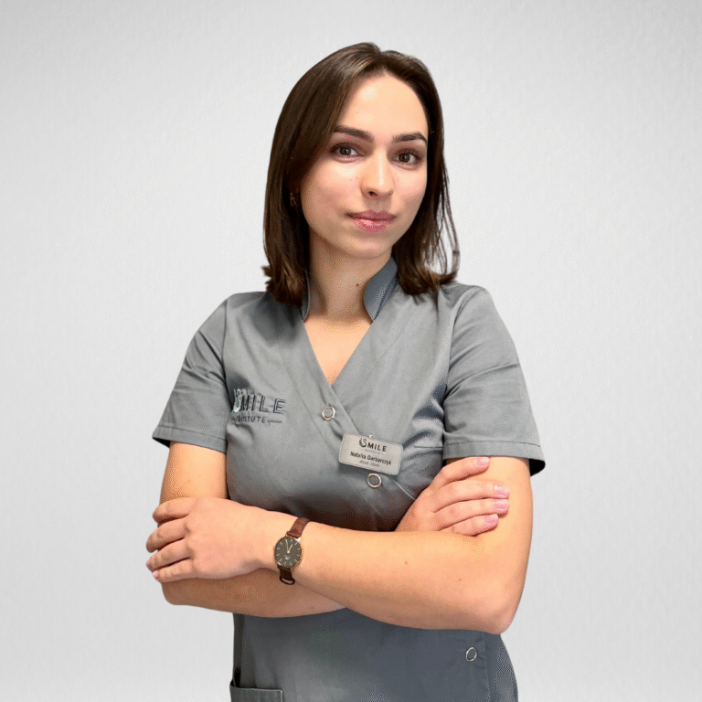 Higienistka Stomatologiczna Natalia Garbarczyk w szarym fartuchu z plakietką oraz logo Smile Instiute